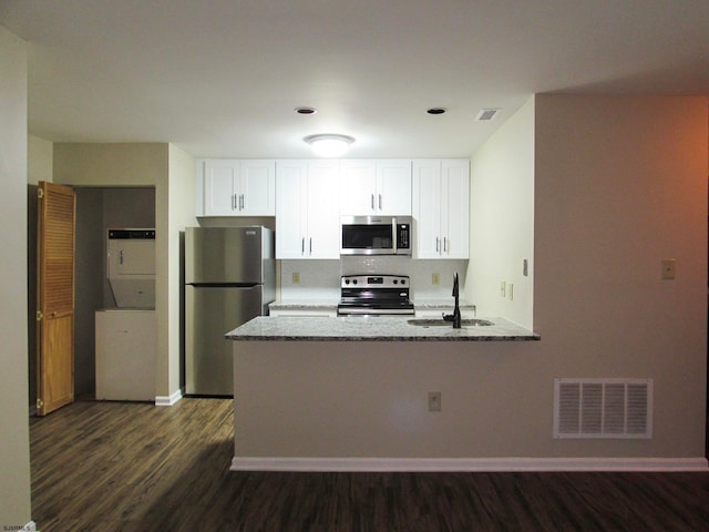 kitchen with white cabinets, sink, dark hardwood / wood-style floors, light stone countertops, and stainless steel appliances