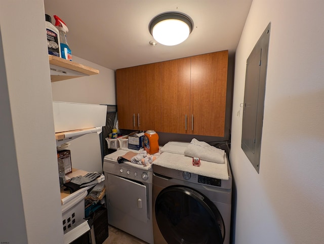 clothes washing area featuring electric panel, cabinets, and independent washer and dryer