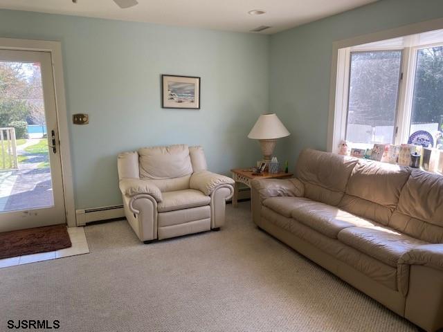 carpeted living room with baseboard heating and ceiling fan