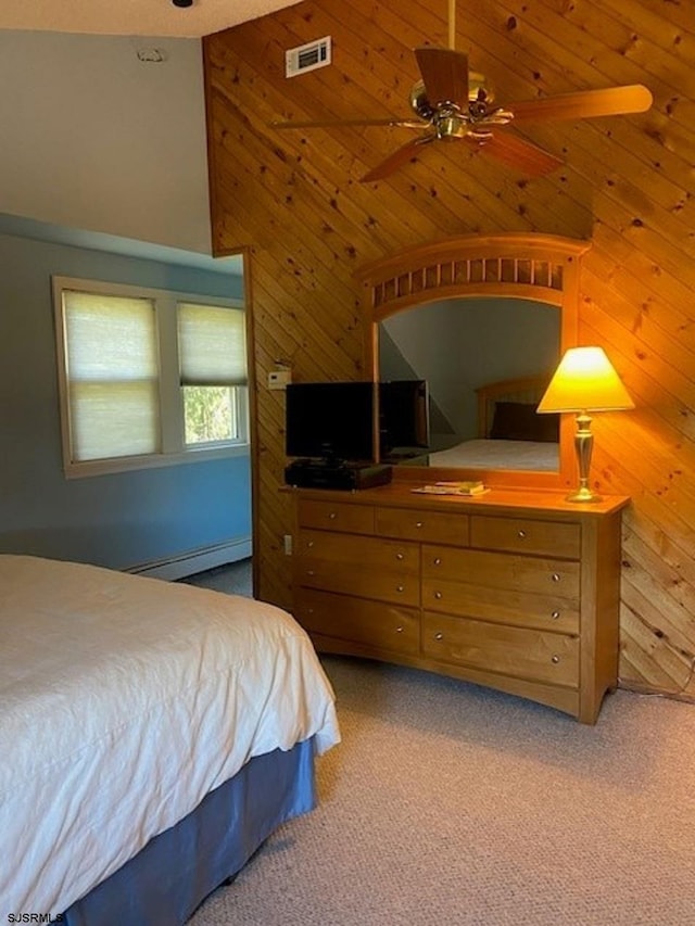 bedroom with carpet flooring, a towering ceiling, a baseboard heating unit, and wood walls