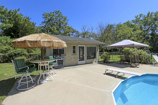 view of swimming pool featuring a grill, a diving board, and a patio