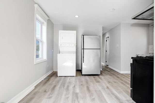 kitchen featuring stainless steel refrigerator, stacked washer and dryer, and light hardwood / wood-style floors