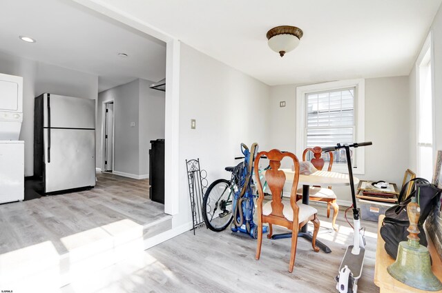 dining area with light wood-type flooring and stacked washer / drying machine