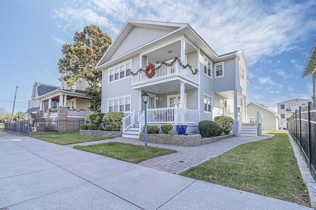 view of front of home with a porch, a balcony, and a front yard