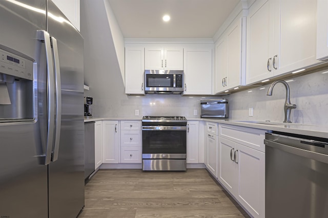 kitchen with backsplash, white cabinets, sink, appliances with stainless steel finishes, and dark hardwood / wood-style flooring