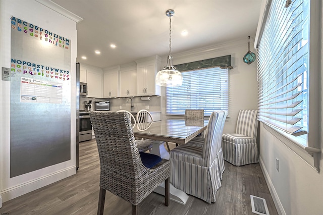 dining area with sink, crown molding, and dark wood-type flooring