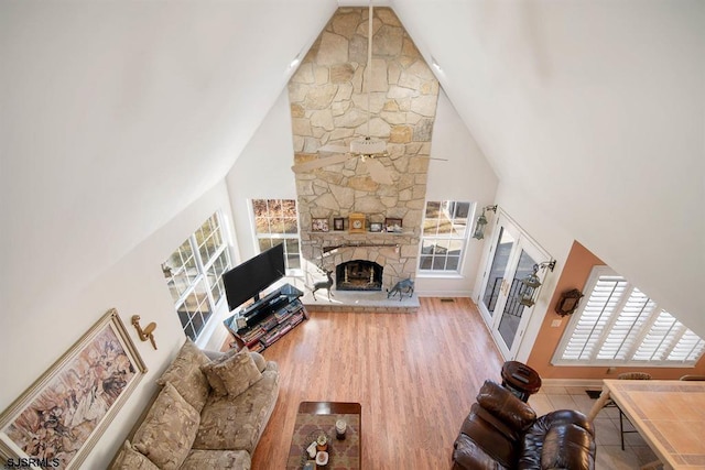 unfurnished living room featuring a fireplace, high vaulted ceiling, and light hardwood / wood-style floors