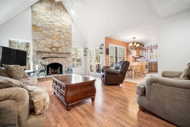 living room with ceiling fan with notable chandelier, high vaulted ceiling, light hardwood / wood-style flooring, and plenty of natural light