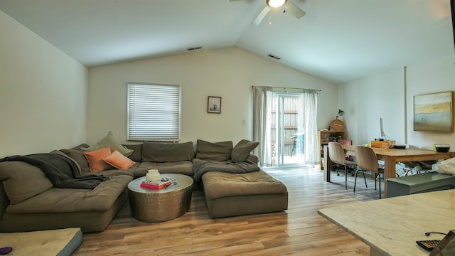 living room with ceiling fan, vaulted ceiling, and light wood-type flooring