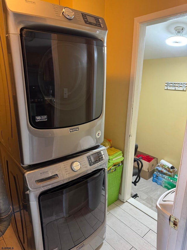 laundry room featuring light tile patterned floors and stacked washer and dryer