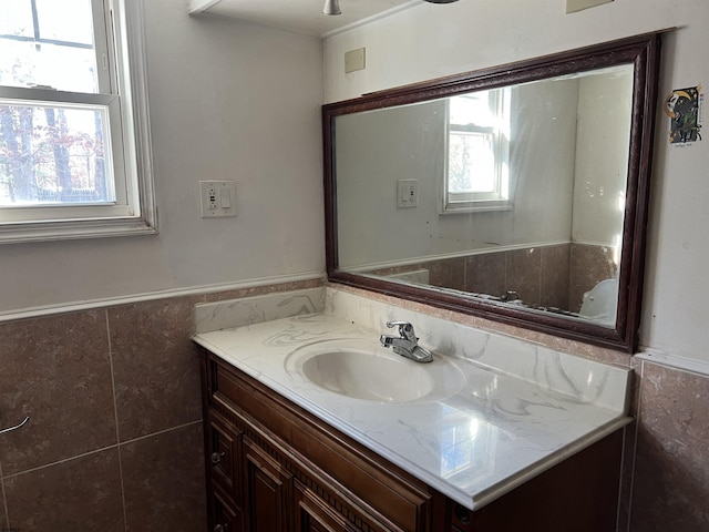 bathroom with vanity, plenty of natural light, and tile walls