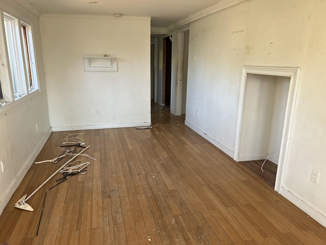 empty room with hardwood / wood-style flooring and ornamental molding