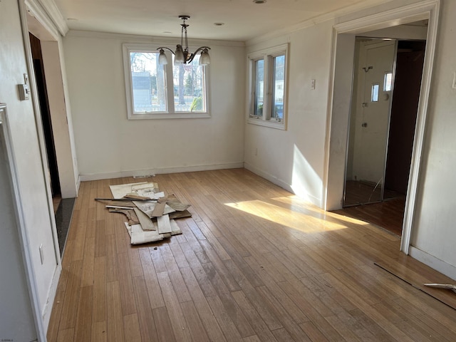 unfurnished dining area featuring light hardwood / wood-style flooring, a notable chandelier, and crown molding