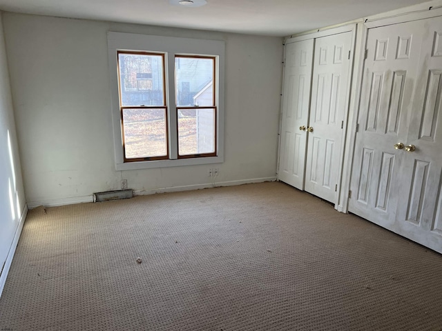 unfurnished bedroom featuring light colored carpet and multiple closets