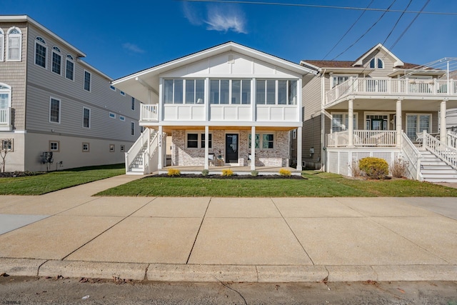 view of front of house featuring covered porch, a front lawn, and a sunroom