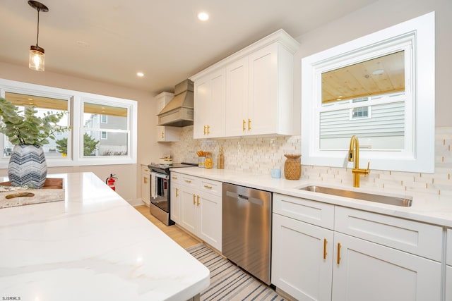 kitchen featuring premium range hood, white cabinets, sink, hanging light fixtures, and stainless steel appliances