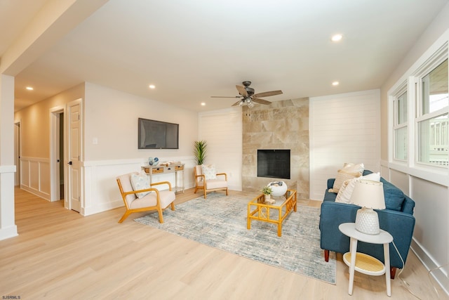 living room featuring a fireplace, light hardwood / wood-style flooring, and ceiling fan