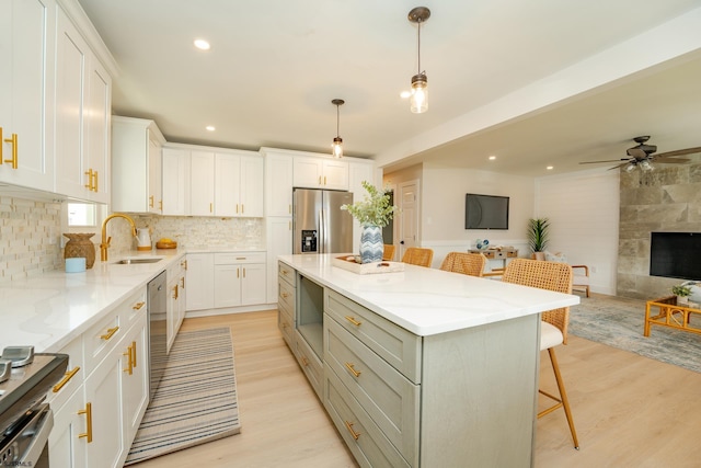 kitchen featuring a kitchen breakfast bar, sink, white cabinetry, a kitchen island, and stainless steel fridge with ice dispenser