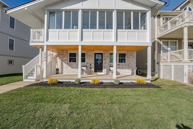 view of front of house with a sunroom, a front lawn, and a porch