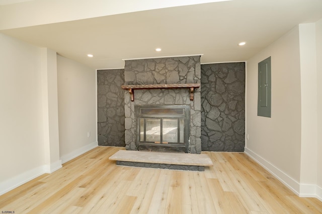 unfurnished living room with a fireplace, electric panel, and light hardwood / wood-style flooring