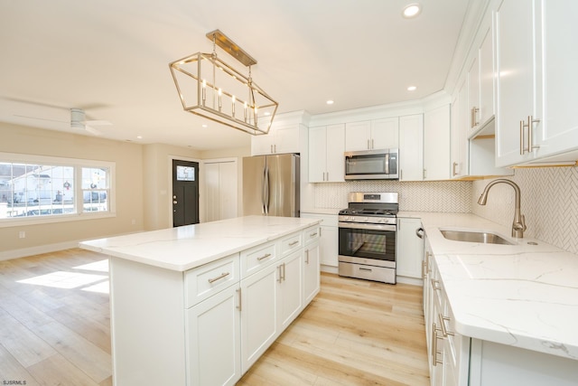 kitchen with a kitchen island, hanging light fixtures, appliances with stainless steel finishes, and light hardwood / wood-style flooring