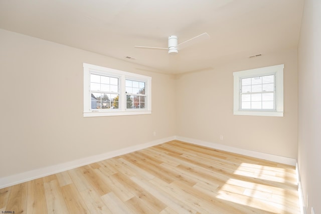 empty room with ceiling fan, plenty of natural light, and light wood-type flooring