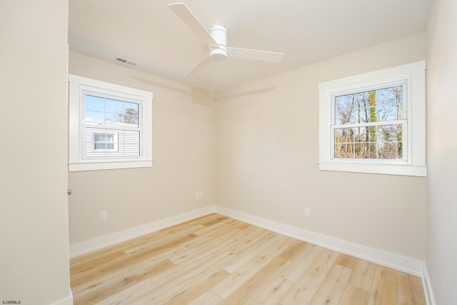 empty room featuring plenty of natural light, ceiling fan, and light wood-type flooring