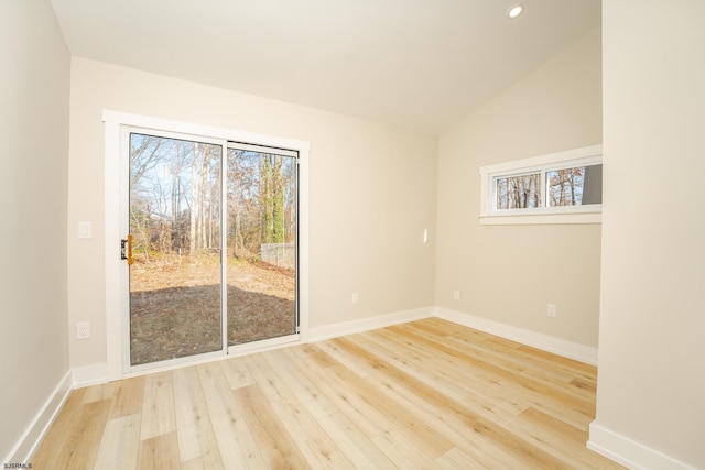 empty room featuring a healthy amount of sunlight, light hardwood / wood-style floors, and vaulted ceiling