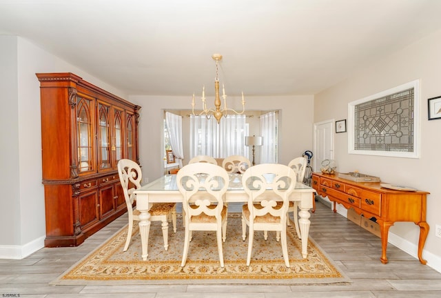 dining space with light hardwood / wood-style floors and an inviting chandelier