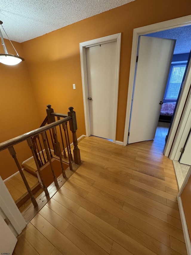 stairs with a textured ceiling and hardwood / wood-style flooring