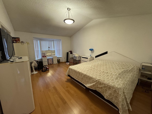 bedroom featuring a textured ceiling, light hardwood / wood-style flooring, and lofted ceiling