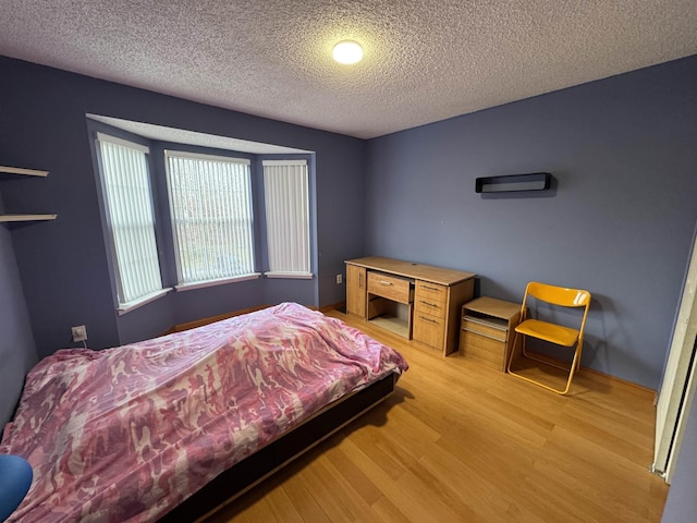 bedroom featuring a textured ceiling and light hardwood / wood-style flooring