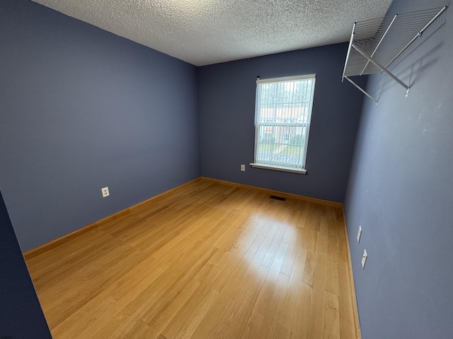 empty room with a textured ceiling and hardwood / wood-style flooring