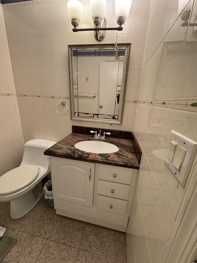 bathroom featuring vanity, toilet, and tile walls