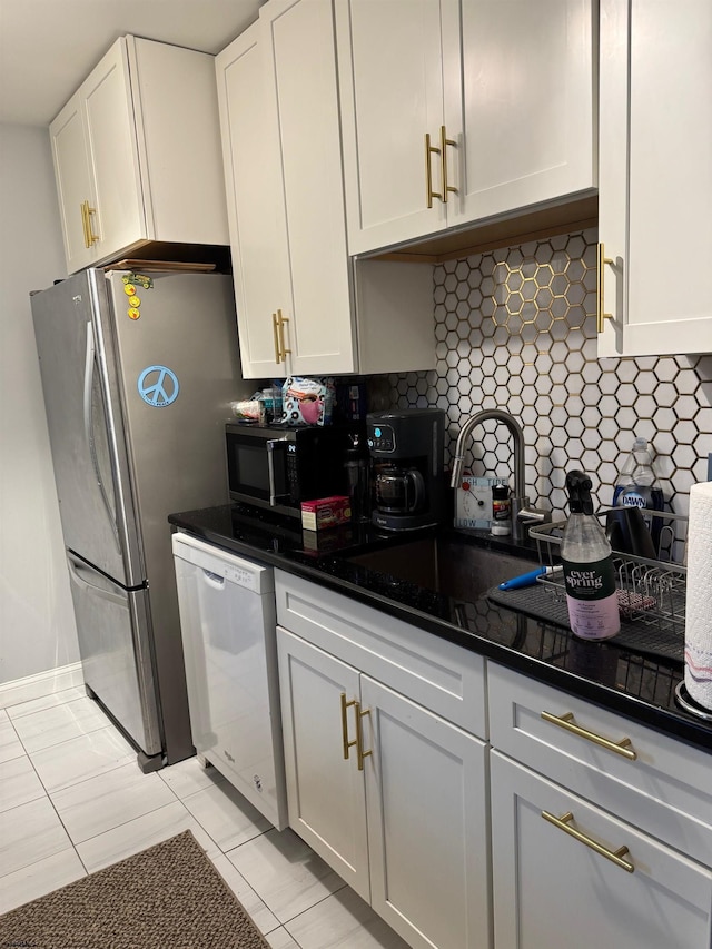 kitchen featuring light tile patterned floors, dark stone countertops, appliances with stainless steel finishes, decorative backsplash, and white cabinets