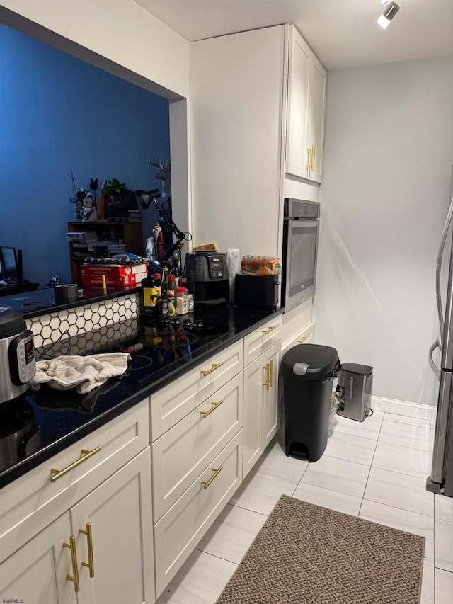 kitchen with white cabinetry, light tile patterned floors, dark stone countertops, and appliances with stainless steel finishes