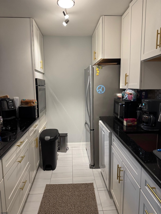 kitchen with white cabinetry, appliances with stainless steel finishes, and dark stone counters