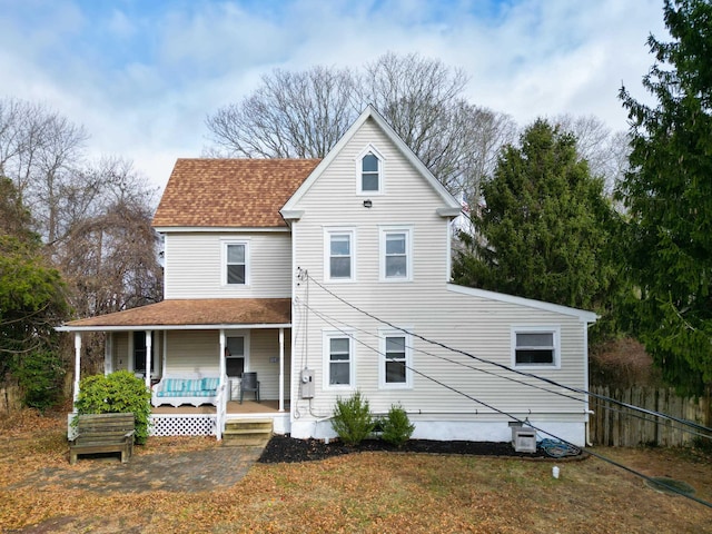 back of property featuring covered porch and a yard