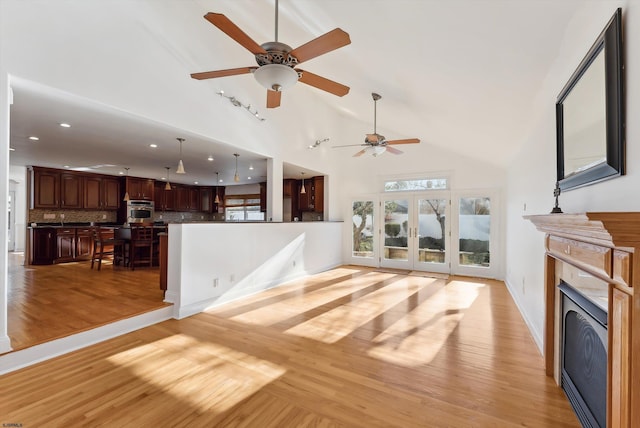 living room featuring ceiling fan, high vaulted ceiling, and light hardwood / wood-style flooring