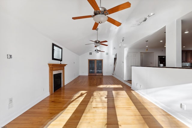 unfurnished living room with hardwood / wood-style flooring, high vaulted ceiling, and ceiling fan