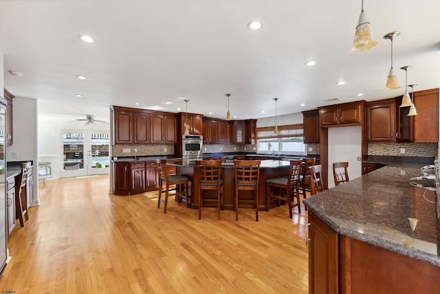 kitchen featuring decorative light fixtures, light hardwood / wood-style flooring, and a healthy amount of sunlight