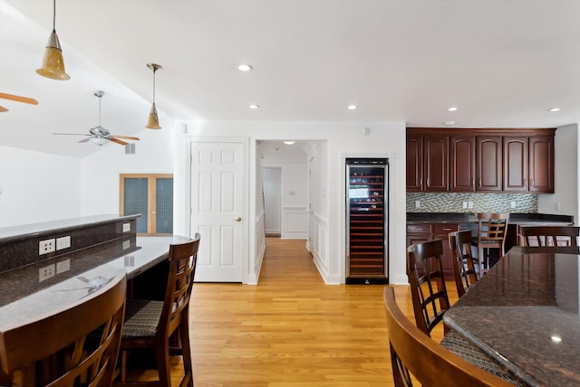 kitchen featuring hanging light fixtures, ceiling fan, decorative backsplash, light hardwood / wood-style floors, and beverage cooler