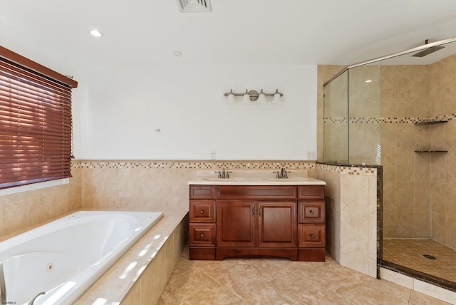 bathroom featuring shower with separate bathtub, vanity, tile patterned floors, and tile walls