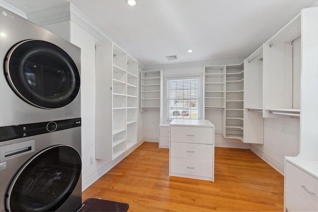 clothes washing area with light hardwood / wood-style flooring and stacked washer and clothes dryer