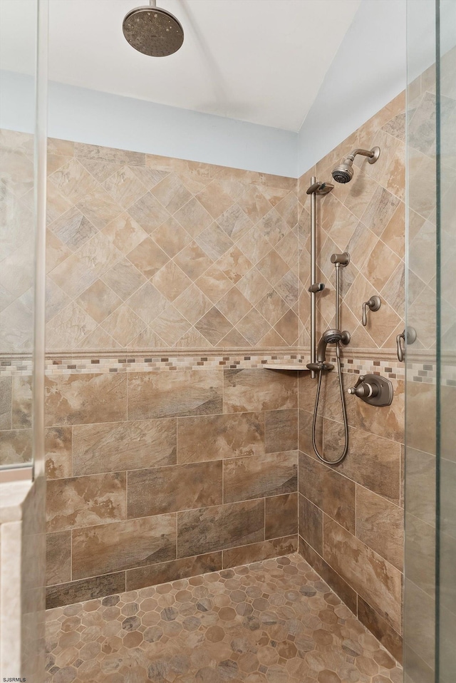 bathroom with a tile shower and vaulted ceiling