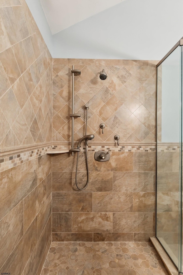 bathroom with a tile shower and lofted ceiling