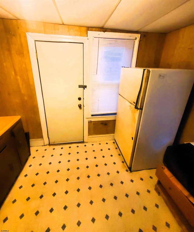 kitchen featuring a paneled ceiling, wood walls, and white fridge