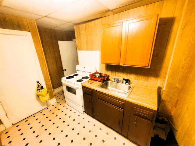 kitchen featuring a paneled ceiling, wood walls, electric stove, and sink