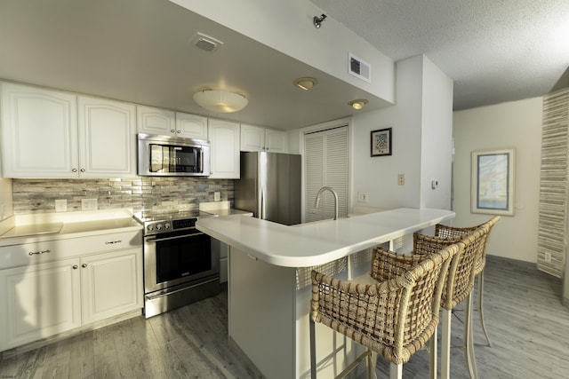 kitchen with a center island, stainless steel appliances, a kitchen breakfast bar, decorative backsplash, and white cabinets