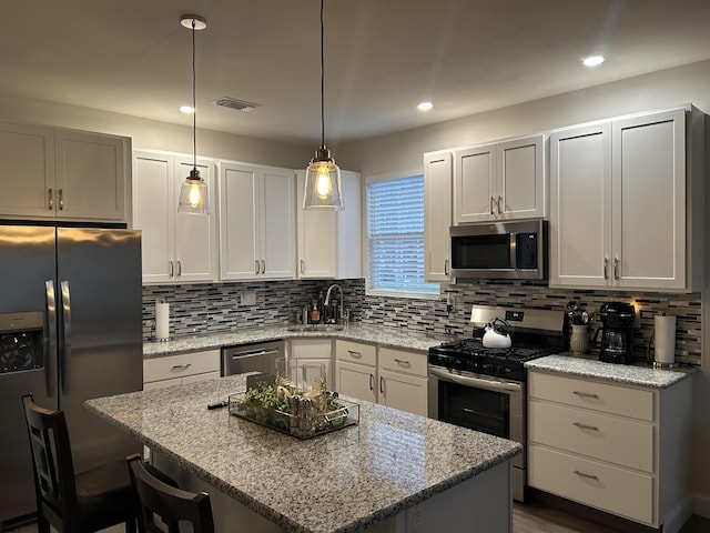 kitchen with pendant lighting, a center island, light stone countertops, and stainless steel appliances